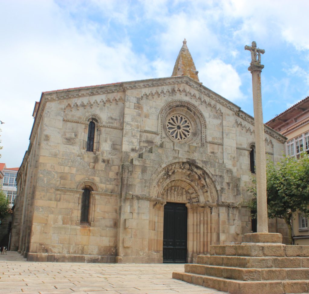 Porta principal da Colexiata de Santa María do Campo xunto ao seu cruceiro.